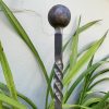 Solid forged ball on top of a wrought iron garden spike.