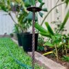 Wrought iron garden spike protects a garden bed.